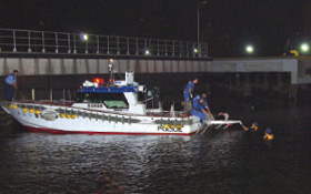 男性を警察警備艇に引き揚げる様子