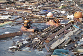 大量の海上浮遊物を掻き分けて、行方不明者を捜索する潜水士(平成23年3月19日、岩手県田野畑村)