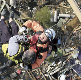 ヘリコプターによる吊り上げによって、孤立した家屋から住民を救助する機動救難士(平成23年3月13日、宮城県石巻市)