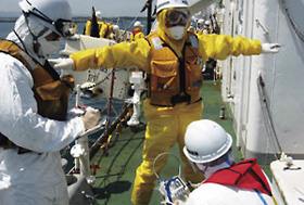 福島第一原子力発電所付近の捜索に従事した海上保安官に対し、放射線量を測定する機動防除隊員(平成23年5月25日、福島県請戸漁港)